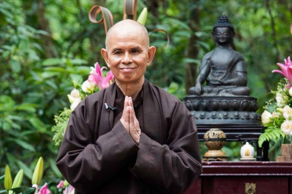 Thich Nhat Hanh in bruine monnikkleding met handpalmen tegen elkaar voor het hart